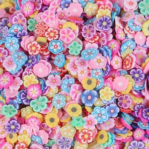 Puede incluir: Un gran surtido de abalorios de arcilla polimérica con forma de flor de colores. Los abalorios son de varios colores, incluyendo rosa, morado, azul, verde, amarillo y naranja. Los abalorios son perfectos para añadir un toque de fantasía a las joyas, las manualidades y otros proyectos.