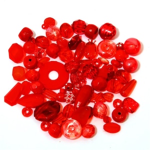 May include: A large assortment of red glass beads in various shapes and sizes. The beads are perfect for jewelry making, crafting, and other creative projects.