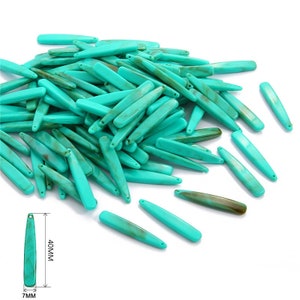 May include: A large pile of turquoise blue, long, flat, and pointed plastic beads. The beads are approximately 40 mm long and 7 mm wide.