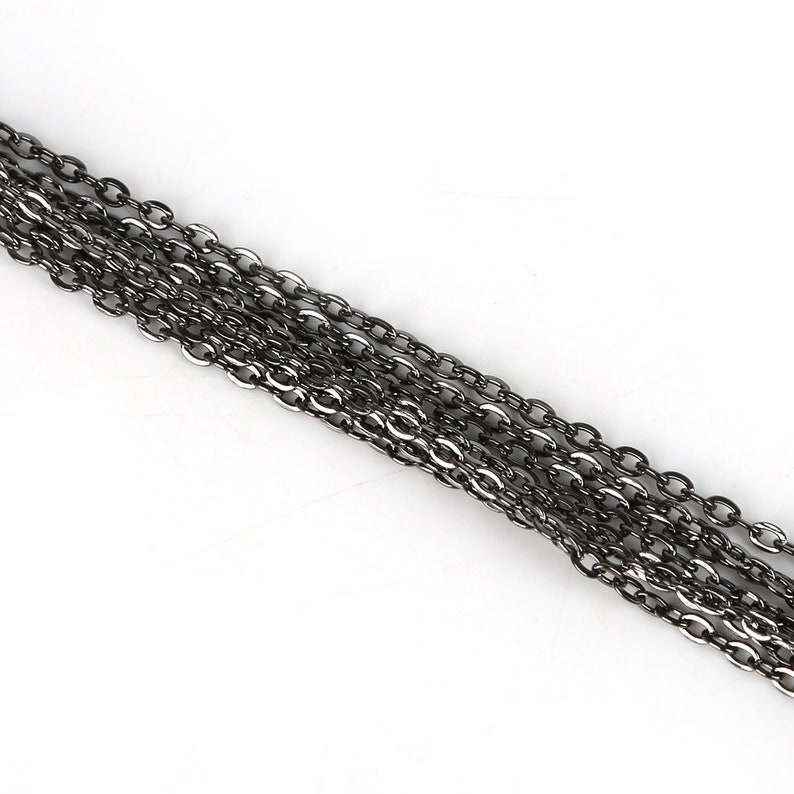 May include: A close-up of a silver chain with multiple strands. The chain is made of small, oval-shaped links.