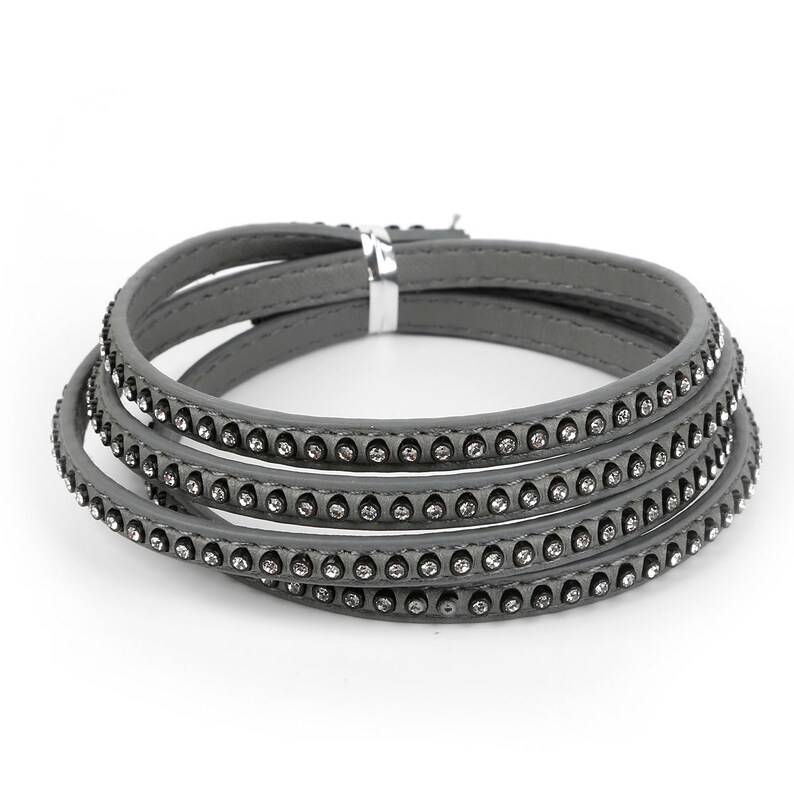 May include: A gray leather bracelet with a row of rhinestones around the edge. The bracelet is made of multiple layers of leather.