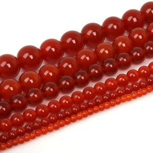 May include: A strand of red carnelian beads in various sizes. The beads are round and smooth, with a polished finish.