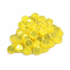 Może przedstawiać: Stosik jasnożółtych plastikowych guzików. Guziki są okrągłe i mają gładkie, błyszczące wykończenie.