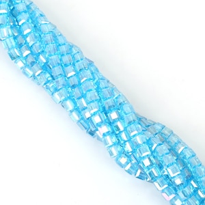 May include: A strand of light blue square glass beads. The beads are faceted and have a slight iridescent shimmer.