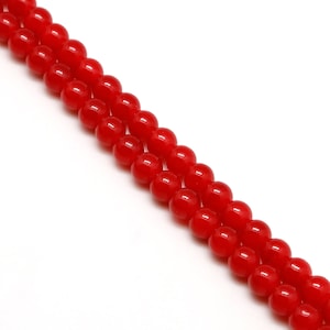 Può includere: Una collana di perline rotonde di colore rosso brillante. Le perline sono infilate su un filo trasparente e sono tutte della stessa dimensione.