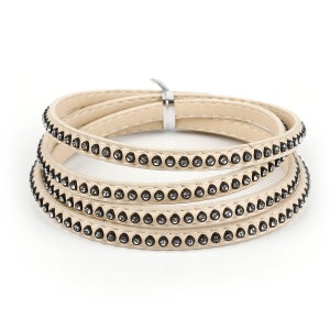 May include: A set of four beige leather bracelets with a row of small rhinestones around the edge of each bracelet.