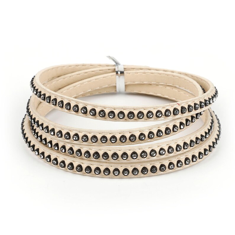 May include: A set of four beige leather bracelets with a row of small rhinestones around the edge of each bracelet.