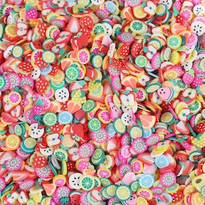 Könnte beinhalten: Eine große Sammlung von bunten, fruchtigen Polymer Clay Charms. Die Charms haben verschiedene Formen, darunter Erdbeeren, Zitronen, Wassermelonen und Ananas. Die Charms sind perfekt, um Schmuck, Schlüsselanhängern oder anderen Bastelarbeiten eine Prise Verspieltheit zu verleihen.