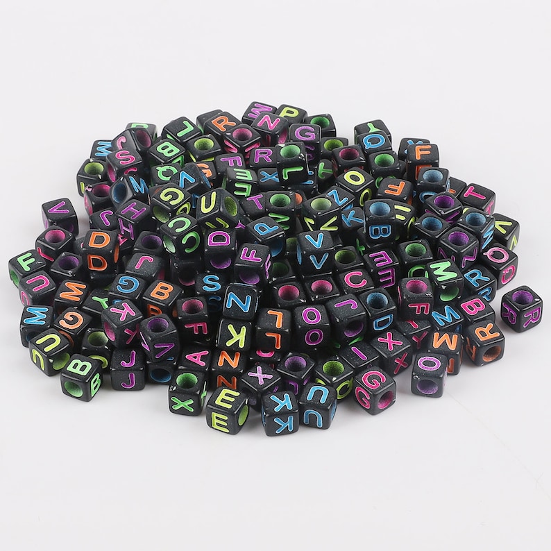 May include: A large pile of black letter beads with colorful letters. The beads are made of plastic and are about 1 cm in size.