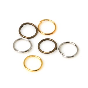 May include: Six jump rings in three different colours: gold, silver, and bronze. The rings are all the same size and are arranged in a random pattern.