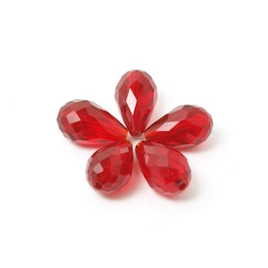 May include: Five red teardrop-shaped crystal beads arranged in a flower shape.