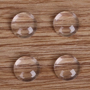 May include: Four clear glass round buttons on a wood surface.