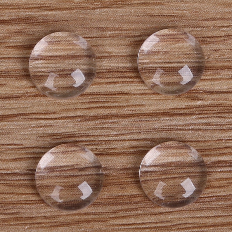 May include: Four clear glass round buttons on a wood surface.