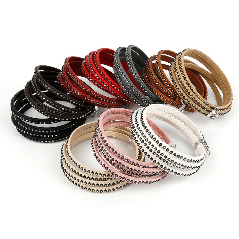 May include: A set of 10 leather bracelets with rhinestones. The bracelets are in various colors, including black, brown, red, gray, beige, pink, and white.