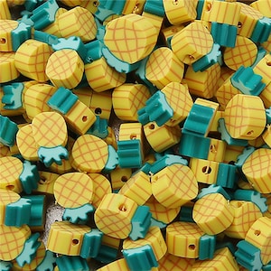 Puede incluir: Primer plano de un montón de cuentas de plástico en forma de piña de color amarillo y verde. Las cuentas tienen una superficie texturizada. Son perfectas para hacer joyas u otras manualidades.