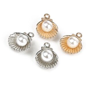 May include: Four gold and silver shell charms with a white pearl in each. The charms have a loop at the top for attaching to jewellery.