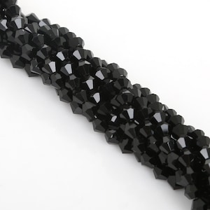Puede incluir: Una hebra de cuentas de cristal negro, cada cuenta es facetada y tiene una forma puntiaguda.