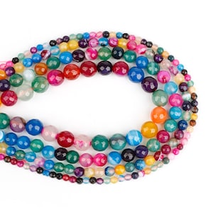 May include: A strand of colourful agate beads, featuring a variety of patterns and shades of blue, green, red, yellow, and purple. The beads are faceted and have a polished finish.