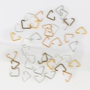 May include: Assortment of silver, gold, and bronze triangle jump rings. The jump rings are small and perfect for jewellery making.
