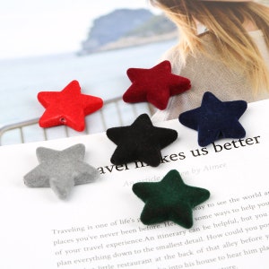 May include: Five velvet star-shaped embellishments in different colors: red, black, gray, navy blue, and green. The stars are arranged in a semi-circle on a white surface with text about travel.