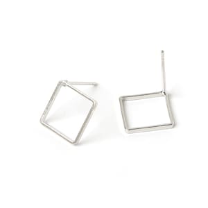 Op de afbeelding: Een paar zilveren vierkante oorbel studs met een eenvoudig ontwerp. De oorbellen zijn gemaakt van metaal en hebben een post achterkant.