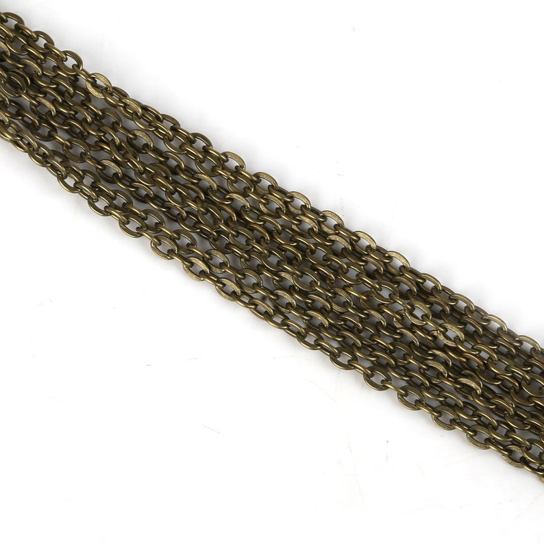 May include: A close-up of a long strand of gold-toned chain. The chain is made of small, oval-shaped links.