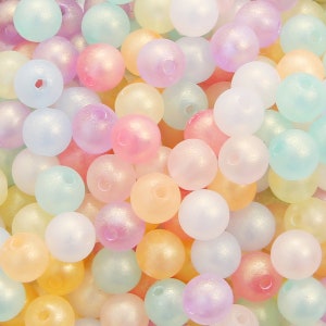 Peut inclure: Un ensemble de perles rondes de couleur pastel avec une finition givrée. Les perles sont en plastique et ont un léger éclat.