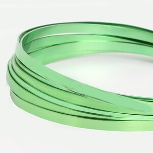 Op de afbeelding: Een close-up van een rol groene metalen draad. De draad is glanzend en heeft een gladde afwerking.