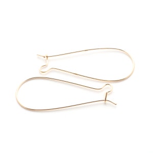 May include: A pair of gold-toned earring wires, also known as French hooks, are shown against a white background.