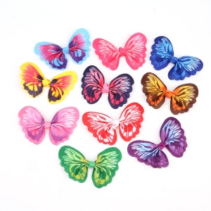 Puede incluir: Surtido de diez pinzas para el pelo con forma de mariposa de colores vivos. Las pinzas están hechas de tela y tienen forma de lazo. Las mariposas son de varios colores, incluyendo rosa, azul, verde, amarillo y morado.