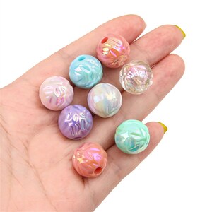 May include: Assortment of iridescent plastic beads in various pastel colors, including pink, blue, purple, and green. The beads have a textured surface and are approximately 1 inch in diameter.