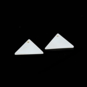 May include: Two white triangle-shaped earrings with a small hole at the top.