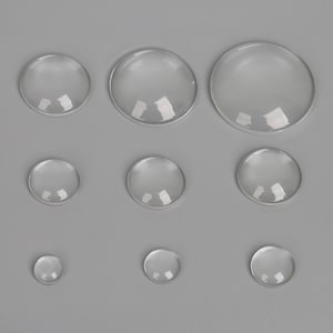 May include: Assortment of clear glass cabochons in various sizes. The cabochons are round and have a smooth, polished surface.