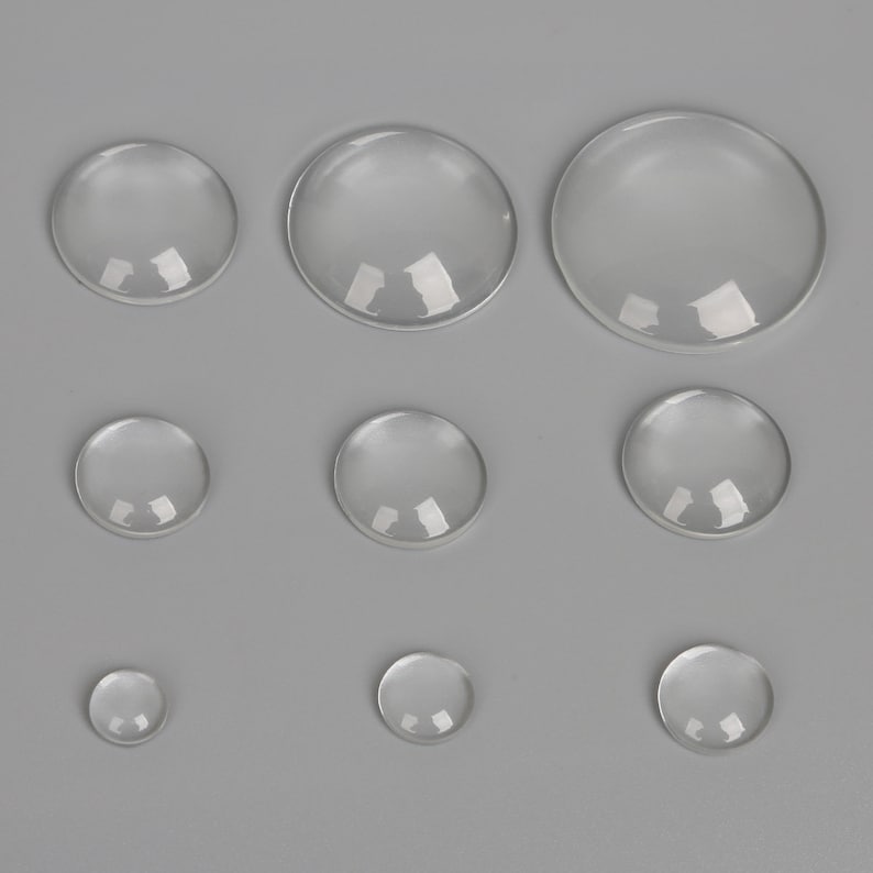 May include: Assortment of clear glass cabochons in various sizes. The cabochons are round and have a smooth, polished surface.