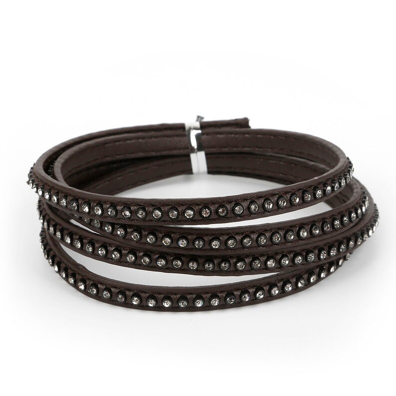 May include: A brown leather bracelet with four rows of clear rhinestones.