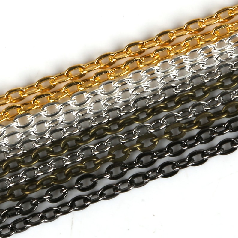 May include: A close-up of five different chain styles in gold, silver, black, and bronze. The chains are arranged in a diagonal line, with the gold chain at the top and the bronze chain at the bottom.