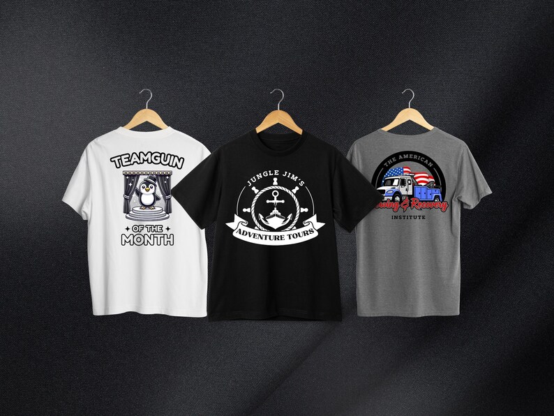 May include: Three t-shirts with different designs. The first t-shirt is white with a penguin illustration and the text "Teamguin of the Month". The second t-shirt is black with a white anchor and the text "Jungle Jim's Adventure Tours". The third t-shirt is gray with a blue truck and the text "The American Towing & Recovery Institute".