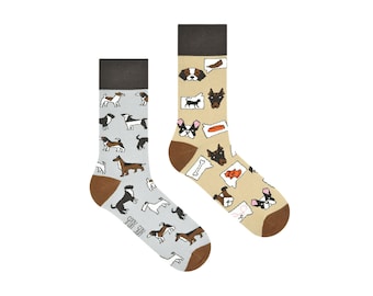 May include: A pair of socks with a dog theme. One sock is light gray with a pattern of various dog breeds. The other sock is beige with a pattern of dogs and dog-related items, including bones, dog treats, and paw prints.