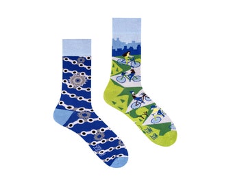 May include: A pair of blue and green socks with a bicycle chain pattern on one sock and a city scene with people riding bicycles on the other sock. The socks are made of cotton and have a ribbed cuff.