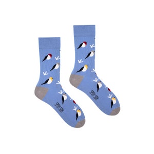 May include: A pair of blue socks with a pattern of colorful birds and snowflakes. The socks have the text "Spox Sox" on the bottom.