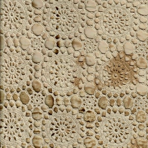May include: A close-up of a crocheted fabric with a repeating pattern of circles. The fabric is a light beige color with a subtle brown pattern.