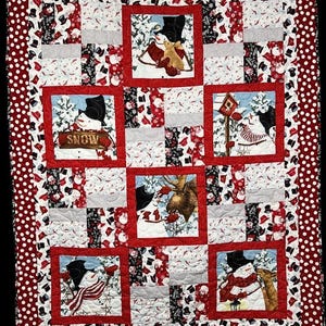 May include: A rectangular quilt featuring a red and white polka dot border and five central square panels depicting snowmen in winter scenes. One panel shows a snowman holding a sign that reads SNOW. The quilt includes red, white, and black fabric.