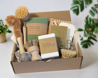 May include: A brown cardboard box filled with zero waste kitchen supplies. The box contains a dish brush, a sponge, a bar of soap, a tea infuser, a set of cloths, and a package of organic reusable no-paper napkins. The box is labeled "Autumn Studio" and "Zero Waste Dishwashing Bar".