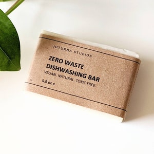 May include: A brown paper-wrapped bar of dish soap with the text "JUTURNA STUDIOS ZERO WASTE DISHWASHING BAR VEGAN. NATURAL. TOXIC FREE. 5.9 oz e" printed on the label.