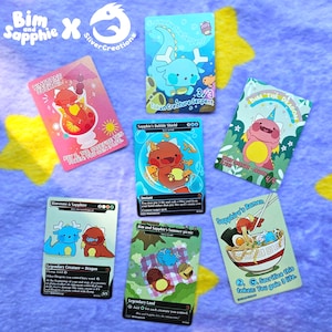 Könnte beinhalten: Eine Sammlung farbenfroher Sammelkarten mit Cartoon-Drachen und anderen skurrilen Charakteren. Die Karten haben verschiedene Designs, darunter einen Cocktail, Ramen und eine Picknick-Szene. Die Karten liegen auf einer lila und gelb sternförmigen Oberfläche.