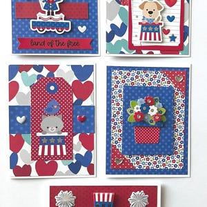 May include: A collection of handmade greeting cards with patriotic themes. Each card features red, white, and blue designs, including illustrations of characters in Uncle Sam hats, flags, and fireworks. Some cards have text that reads "land of the free" and "Happy Independence Day!"