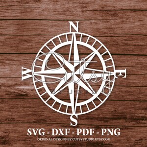 Puede incluir: Rosa de los vientos blanca con las letras N, S, E y W sobre un fondo de madera marrón. El texto "SVG - DXF - PDF - PNG" y "ORIGINAL DESIGNS BY CUTSYSTUDIO.ETSY.COM" está debajo de la rosa de los vientos.