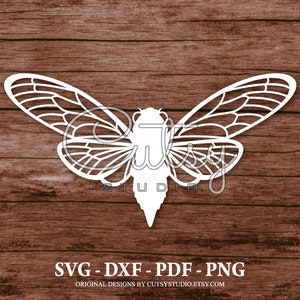 Puede incluir: Un diseño blanco de insecto cigarra con patrones de alas detallados. La imagen incluye el texto "SVG - DXF - PDF - PNG" y "ORIGINAL DESIGNS BY CUTSYSTUDIO.ETSY.COM" sobre un fondo de madera marrón.