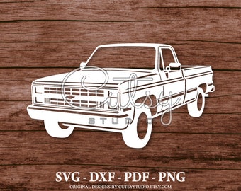 Könnte beinhalten: Eine weiße Silhouette eines klassischen Pick-up-Trucks mit einem schwarzen Kühlergrill und einer schwarzen Stoßstange. Der Truck ist zum Betrachter gerichtet und hat eine große Ladefläche hinten. Das Bild ist vor einem braunen Holzhintergrund platziert.