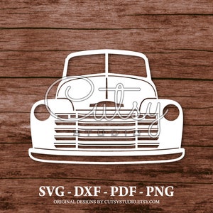 May include: A white silhouette of a vintage pickup truck with a detailed front grille, headlights, and bumper. The truck is isolated against a brown wooden background.